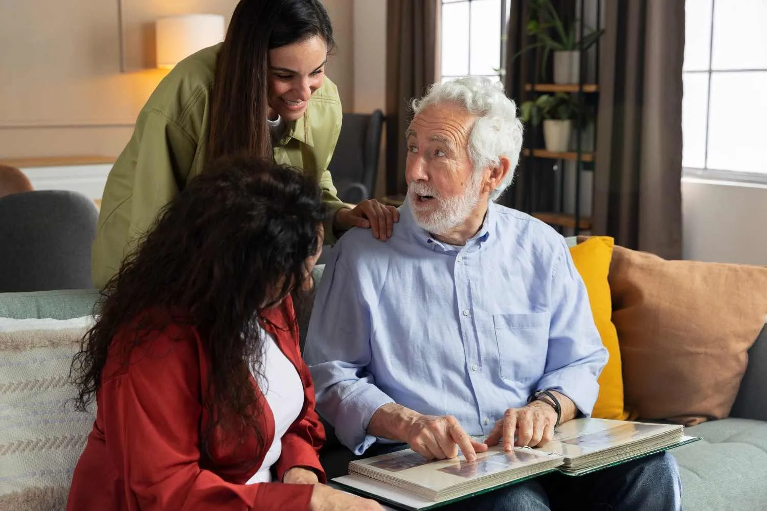 Two women and an older man looking through pages together on a sofa at home